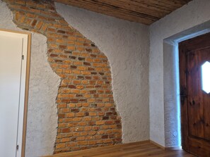Una habitación con pared de ladrillo, puerta y piso de madera.