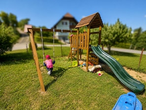 A playground with a swing set, slide, and climbing structure.