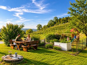 Ein Picknicktisch mit Bänken, ein Spielplatz mit Schaukeln und ein eingezäunter Gartenbereich.