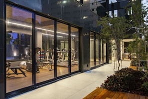 Ein modernes Fitnessstudio mit Trainingsgeräten, großen Fenstern und einem Holzdeck.