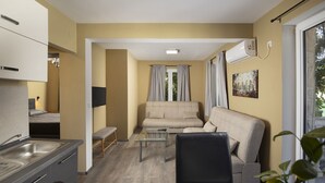 Ett kompakt bostadsutrymme med ett litet kök, en soffa, ett soffbord i glas och en matplats.