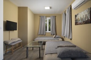 Een kamer met een bed, een bank, een televisie en een raam met gordijnen.