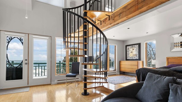 Un intérieur moderne avec un escalier en colimaçon, un balcon offrant une vue agréable et un coin salon confortable.