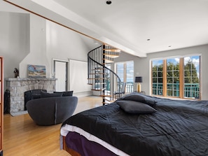 Une chambre spacieuse avec un grand lit, une cheminĂ©e, un escalier et une vue sur lâextĂ©rieur.