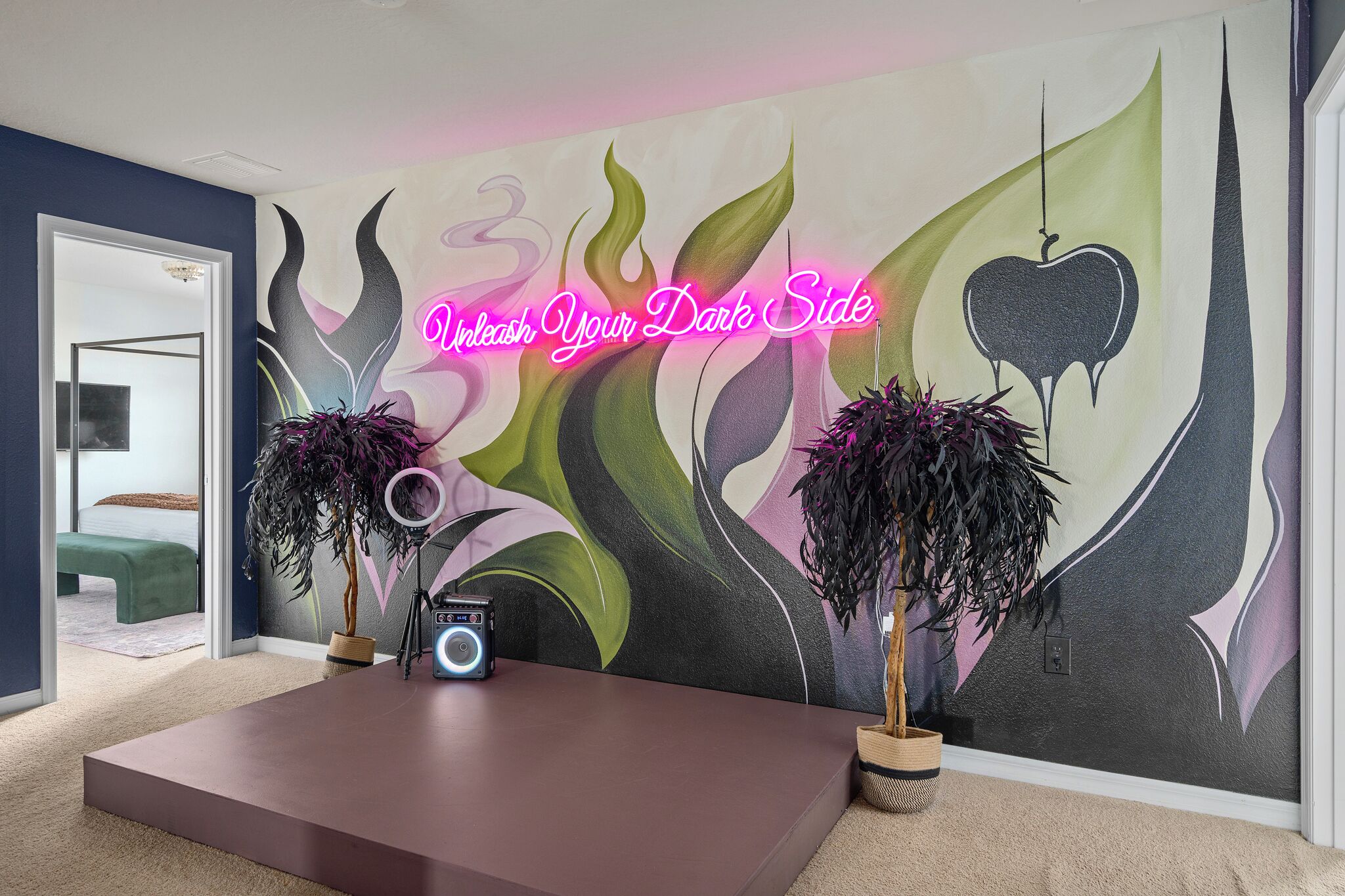 Une pièce avec une grande fresque murale, un bureau avec une radio et deux plantes en pot.