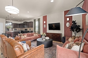 Ein modernes Wohnzimmer mit Ledersofas, einem runden Couchtisch und einem flachbildfernseher an der Wand.