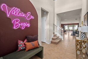 Ein modernes Interieur mit einer Neonreklame, einer Treppe und einer Bank mit dekorativen Kissen.