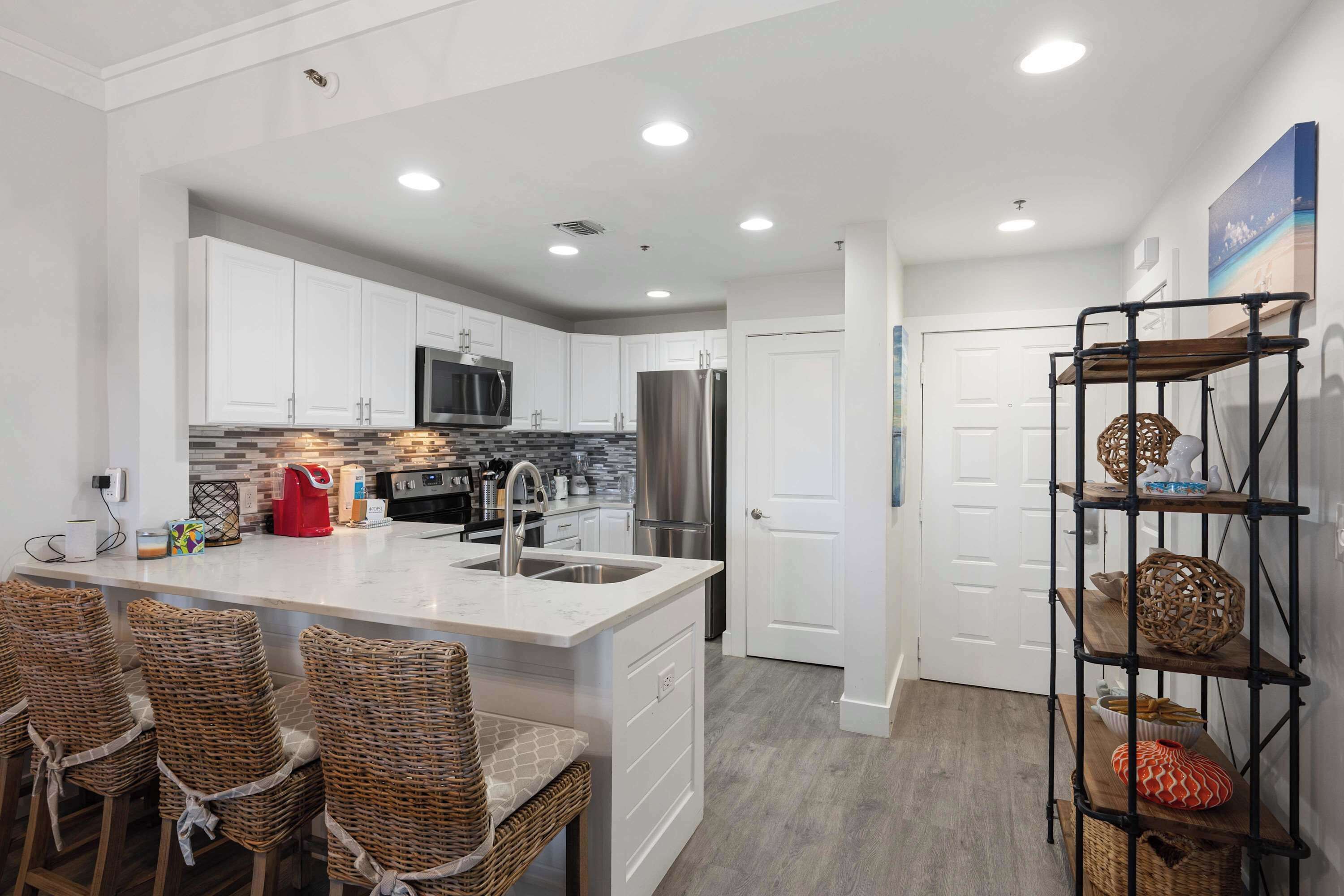 A modern kitchen with white cabinets, stainless steel appliances, and a central island with bar stools.