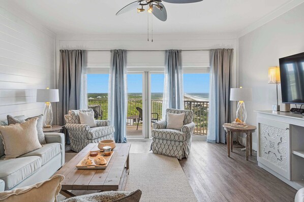 A spacious living room with a sofa, armchairs, a coffee table, and a television. - Spacious beachfront condo with gulf views (Miramar Beach)