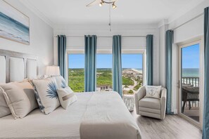 A bedroom with a large bed, a chair, and a balcony with a view. - Spacious beachfront condo with gulf views (Miramar Beach)