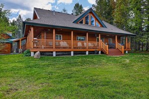 A log cabin with a porch, a staircase, and a grassy yard.