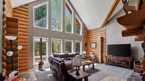 A log cabin interior with a sectional sofa, a TV, and a fireplace. - Golf Course Cabin | Sleeps 16, Hot Tub, Game Room, Golf, 25min to YSNP (Island Park)