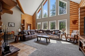 A log cabin interior with a sectional sofa, a coffee table, and a fireplace.