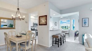 A modern kitchen with a dining area, a bar, and a living space with a view.