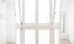 Ein Zimmer mit weißen Wänden, einem weißen Kleiderschrank, einer weißen Tür und einem weißen Hocker.