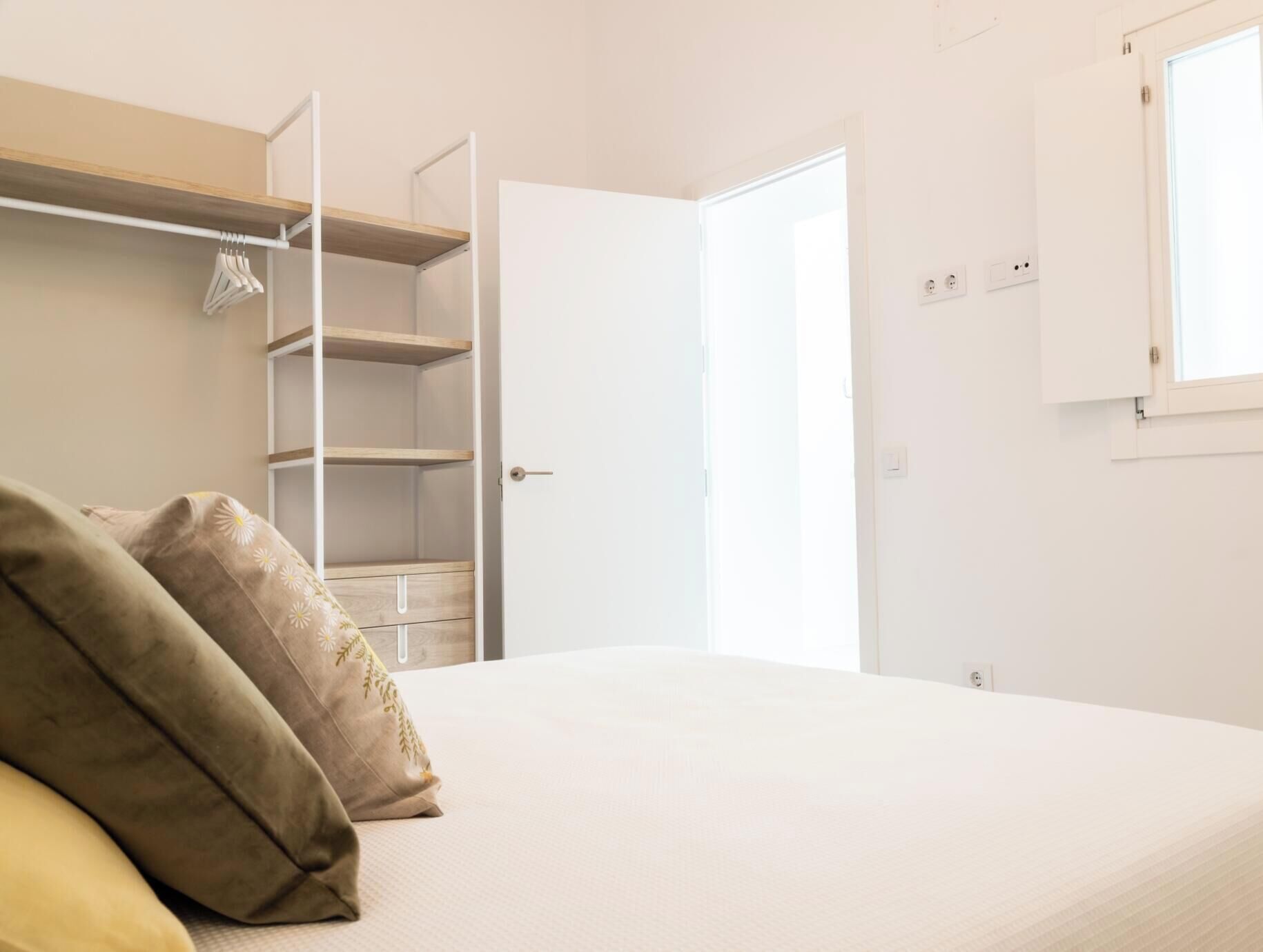 Un dormitori amb un llit, un armari i una porta que condueix a una altra habitació.