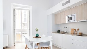 Eine moderne Küche mit weißen Schränken, einer Mikrowelle und einem Essbereich mit einem weißen Tisch und Stühlen.