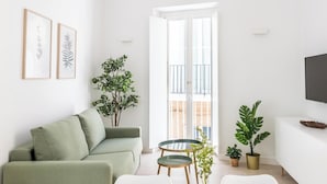 Ein modernes Wohnzimmer mit einer Couch, einem Esstisch und Topfpflanzen.