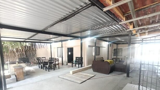A covered outdoor area with tables and chairs, a sofa, and a concrete floor. - Casa Cactus (Linares)