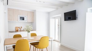 Eine moderne Küche mit weißen Schränken, einer Mikrowelle und einem Essbereich mit Holztisch und gelben Stühlen.