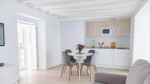 Een moderne keuken met witte kastjes, een magnetron en een houten aanrecht.