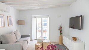 Een moderne woonkamer met een bank, een salontafel, een televisie en een groot raam.