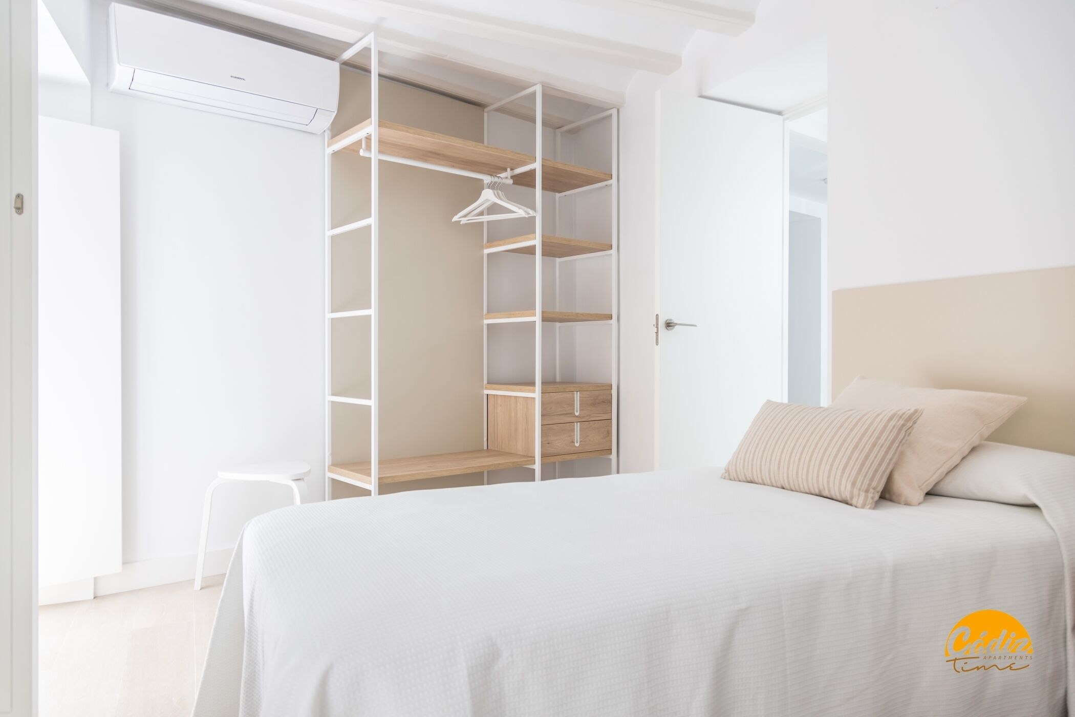Een slaapkamer met een bed, een witte kast en een hangende kledingorganizer.