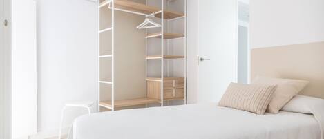Een slaapkamer met een bed, een witte kast en een hangende kledingorganizer.