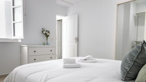 Une chambre à coucher avec un lit, une commode, un miroir et une porte.