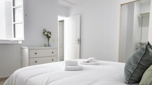 Ein Schlafzimmer mit Bett, Kommode, Spiegel und Tür.