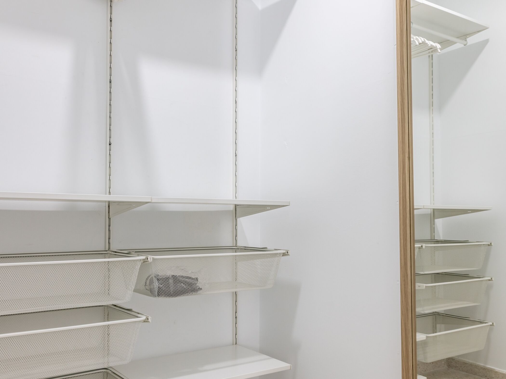 A white interior with metal shelving units and a wooden-framed mirror.