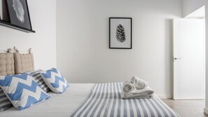 A bedroom with a bed, pillows, a framed pinecone artwork, and a door. - Atico Catedral by Cadiz Time (Cádiz)