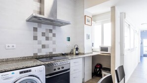 A compact kitchen with a washing machine, a microwave, and a stove. - Atico Catedral by Cadiz Time (Cádiz)