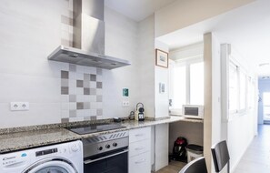 A compact kitchen with a washing machine, a microwave, and a stove. - Atico Catedral by Cadiz Time (Cádiz)