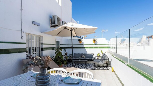 A rooftop terrace with a dining table, chairs, a sofa, and an umbrella. - Atico Catedral by Cadiz Time (Cádiz)