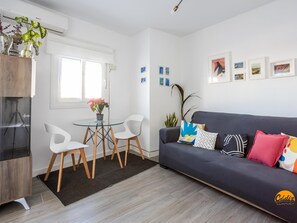 A modern living room with a grey sofa, white chairs, a glass table, and a potted plant. - Atico Catedral by Cadiz Time (Cádiz)