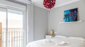 A hotel room with a bed, a painting, a nightstand, and a red hanging decor. - Casa Arcoiris by Cadiz Time (Ciudad de Cádiz)