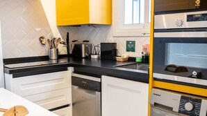 Uma cozinha moderna com máquina de lavar louça, cafeteira e máquina de lavar roupa.
