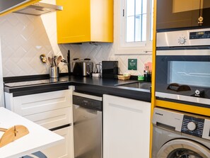 A modern kitchen with a dishwasher, a coffee machine, and a washing machine. - Casa Arcoiris by Cadiz Time (Ciudad de Cádiz)