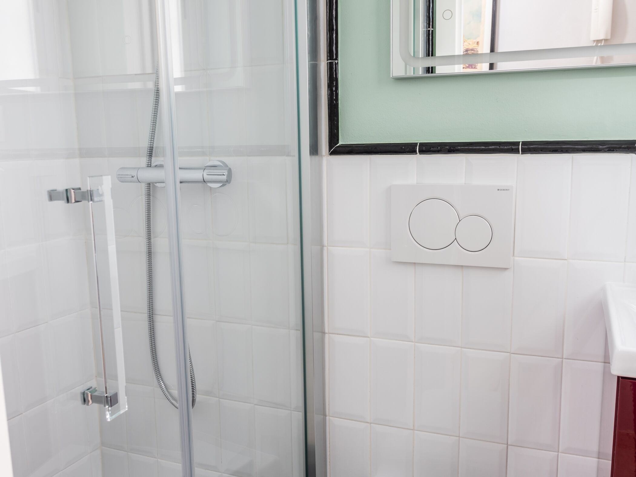 A bathroom with a glass shower enclosure, a towel rack, and a wall-mounted thermostat.