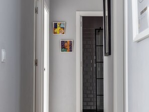 A hallway with a white door, a glass door with a black frame, and two artworks on the wall. - Casa Arcoiris by Cadiz Time (Ciudad de Cádiz)