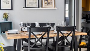 Uma área de jantar com mesa de madeira, cadeiras pretas e quadros na parede.