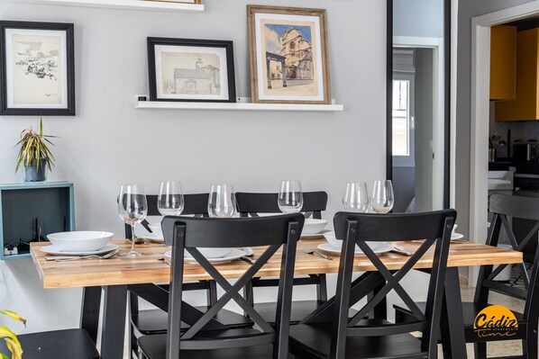 A dining area with a wooden table, black chairs, and framed artwork on the wall. - Casa Arcoiris by Cadiz Time (Ciudad de Cádiz)