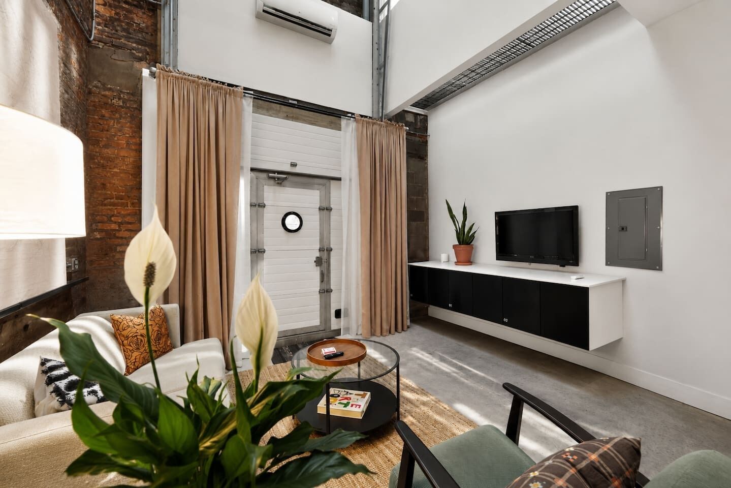 Un salon moderne avec un canapé, une table basse et un téléviseur fixé à un mur blanc.