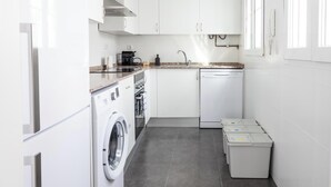 Una cocina funcional equipada con lavadora, lavavajillas y electrodomésticos sobre la encimera.