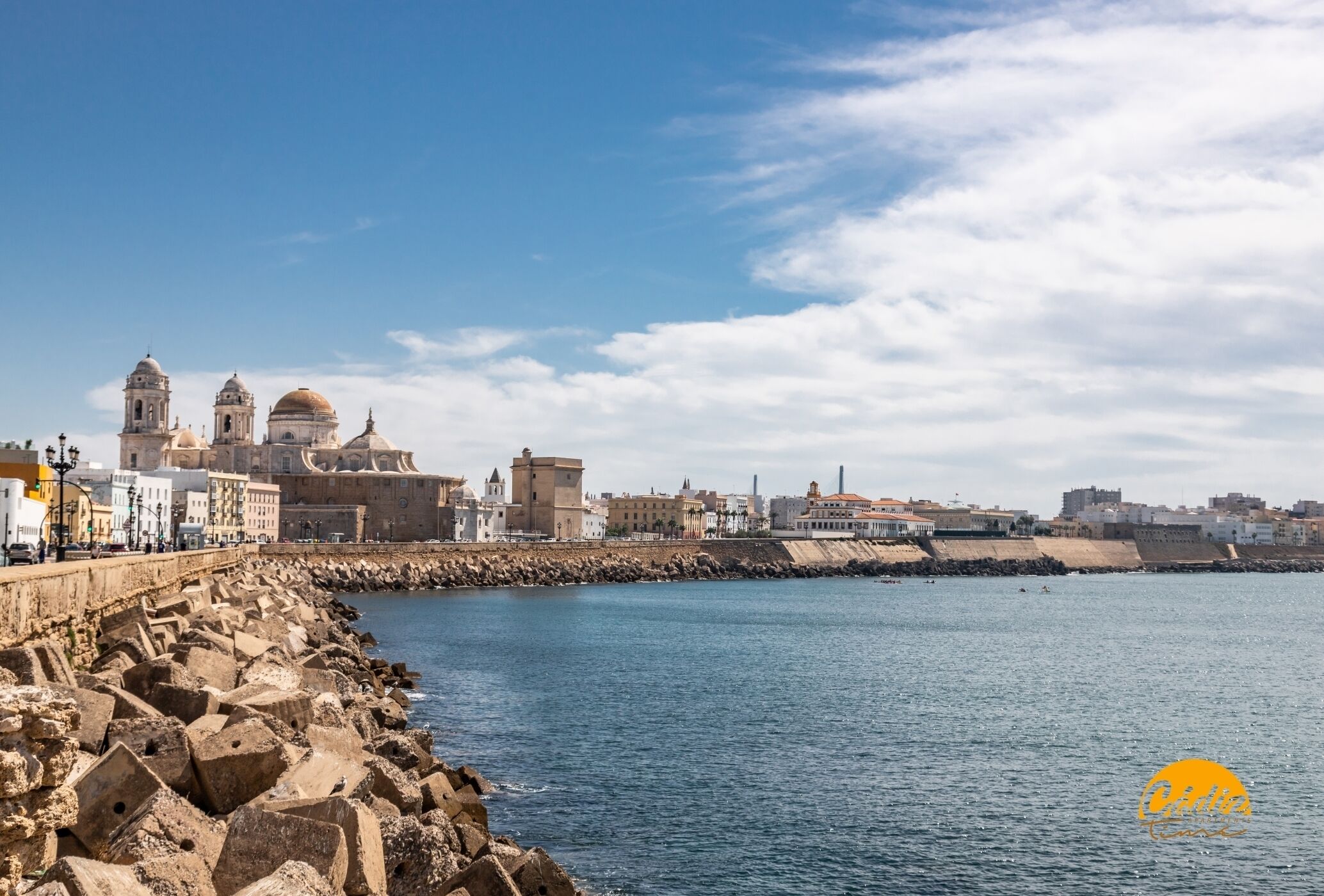 Paesaggio costiero con edifici storici, una chiesa importante e un lungomare roccioso.