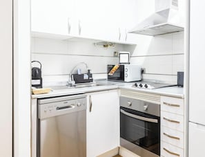 A compact kitchen with a dishwasher, oven, toaster, and kettle. - Rincon del Mar - FREE PARKING by Cadiz Time (Ciudad de Cádiz)
