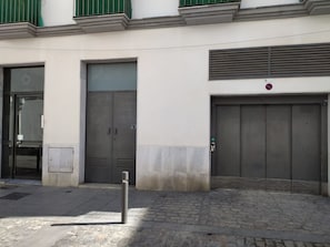 A building with two large grey doors, a small window, and a green awning. - Rincon del Mar - FREE PARKING by Cadiz Time (Ciudad de Cádiz)