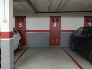 Eine Parkgarage mit nummerierten Türen, ein weißes Auto und ein schwarzes Auto.