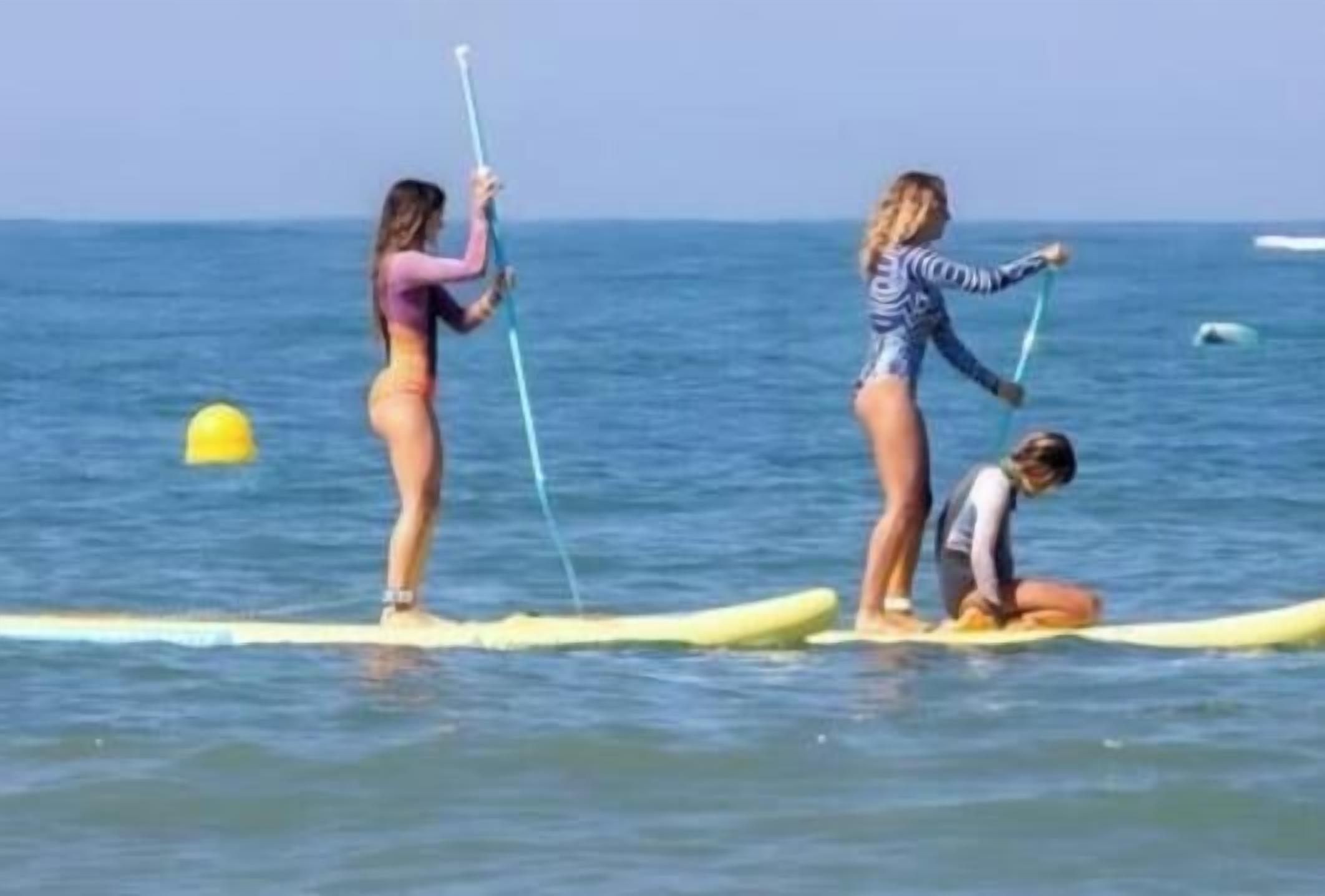 Tres persones en taules de paddle surf a l'aigua.